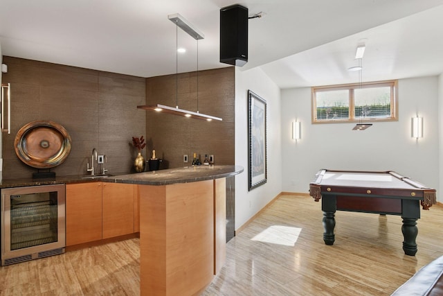 bar with beverage cooler, light wood finished floors, a sink, and wet bar