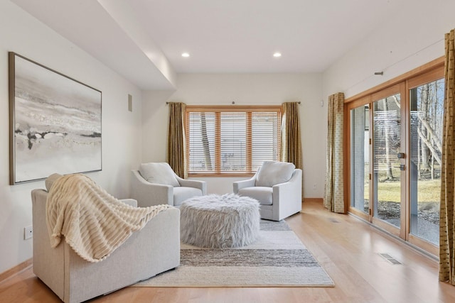 living area with a healthy amount of sunlight, visible vents, and wood finished floors