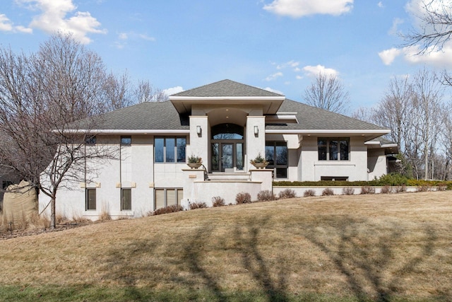 view of front of property featuring a front lawn, a shingled roof, and stucco siding