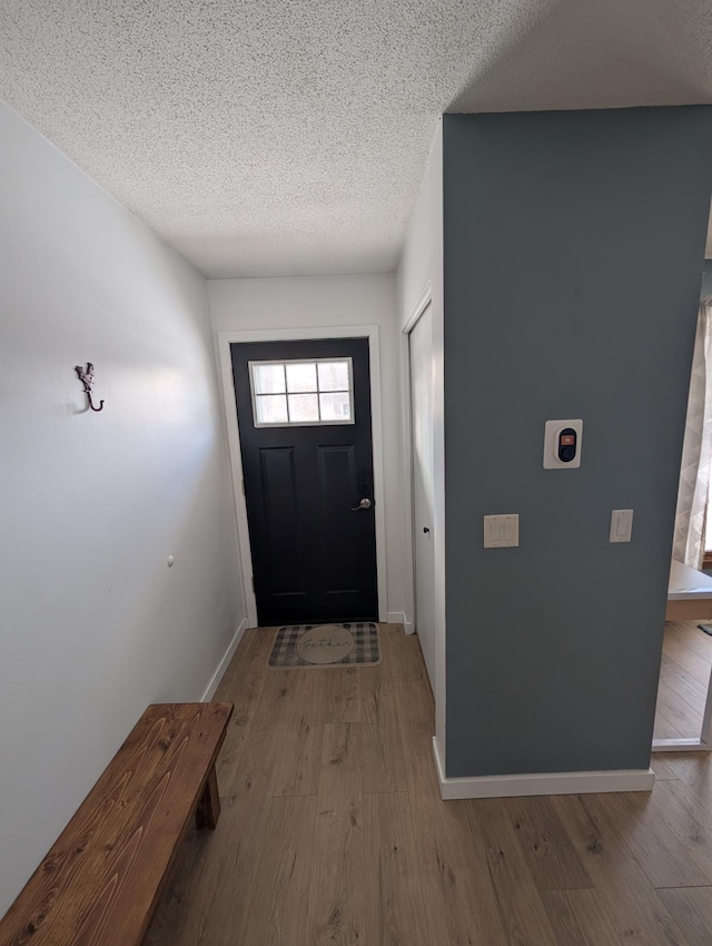 foyer entrance with a textured ceiling and light hardwood / wood-style flooring