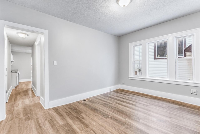 spare room with light hardwood / wood-style flooring and a textured ceiling