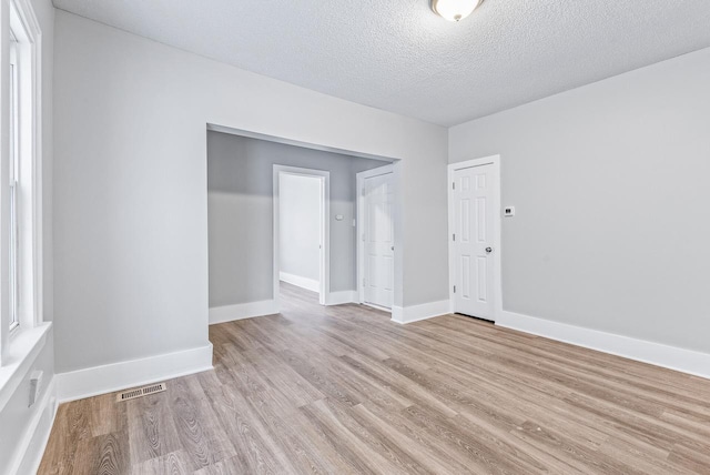 spare room with light hardwood / wood-style flooring and a textured ceiling