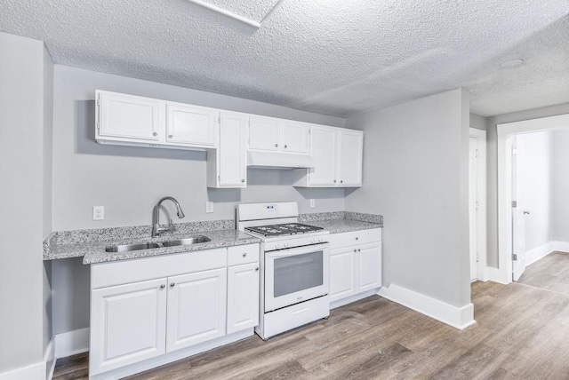 kitchen featuring white cabinetry, sink, light stone counters, white gas range oven, and light wood-type flooring