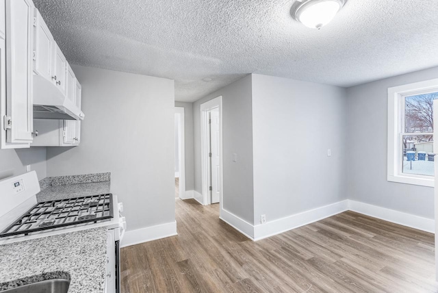 kitchen featuring hardwood / wood-style floors, light stone countertops, a textured ceiling, white cabinets, and white range with gas cooktop