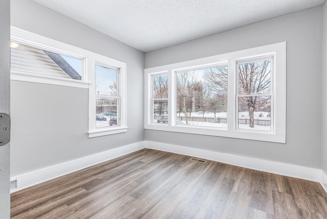 spare room featuring hardwood / wood-style flooring and a textured ceiling