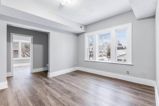 unfurnished room with hardwood / wood-style flooring and a textured ceiling