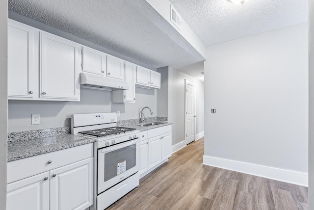 kitchen featuring white cabinetry, white gas range, sink, light stone counters, and light wood-type flooring