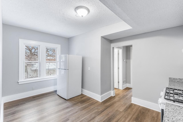 interior space featuring white appliances, a textured ceiling, and hardwood / wood-style flooring