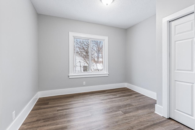 unfurnished room with hardwood / wood-style flooring and a textured ceiling