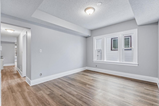 empty room with a textured ceiling and light wood-type flooring