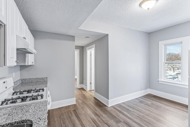 kitchen with white cabinetry, light stone counters, white range with gas stovetop, and light wood-type flooring