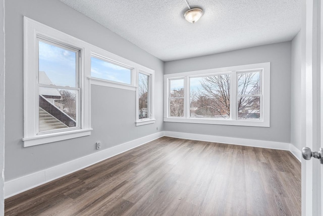 unfurnished room with dark wood-type flooring and a textured ceiling