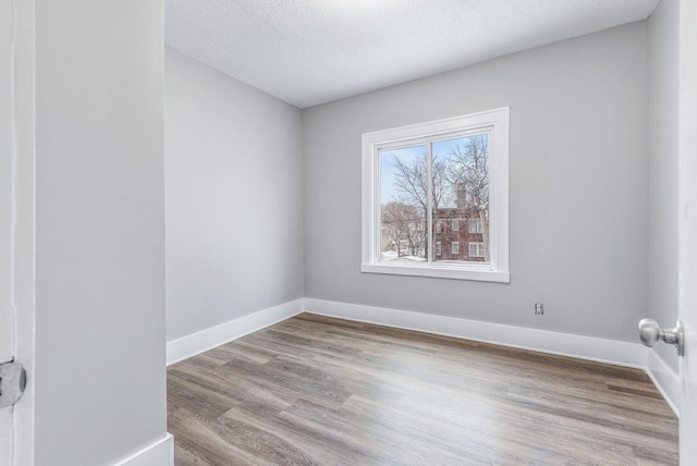 unfurnished room with light hardwood / wood-style flooring and a textured ceiling