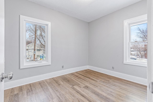 empty room with light hardwood / wood-style flooring and a textured ceiling