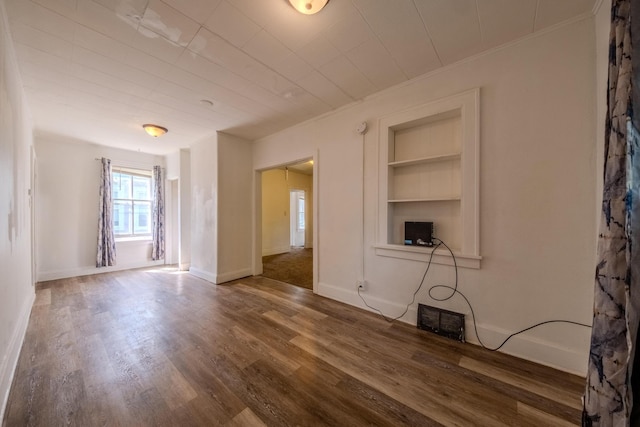 unfurnished living room featuring built in shelves and dark wood-type flooring