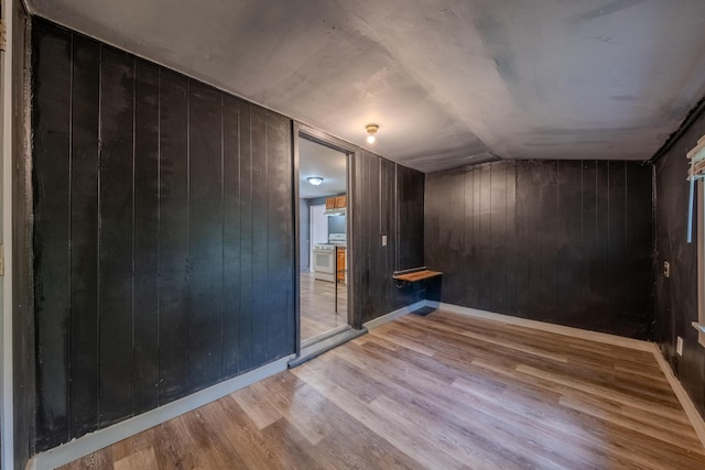 interior space with lofted ceiling, light wood-type flooring, and wood walls