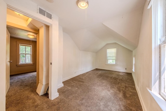 additional living space with vaulted ceiling and dark colored carpet