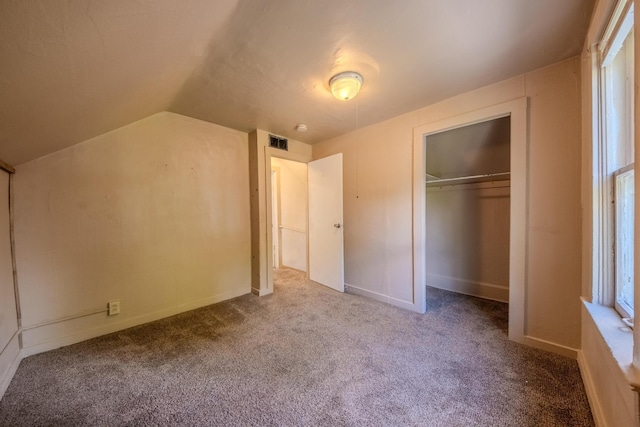 unfurnished bedroom featuring lofted ceiling, carpet, and a closet