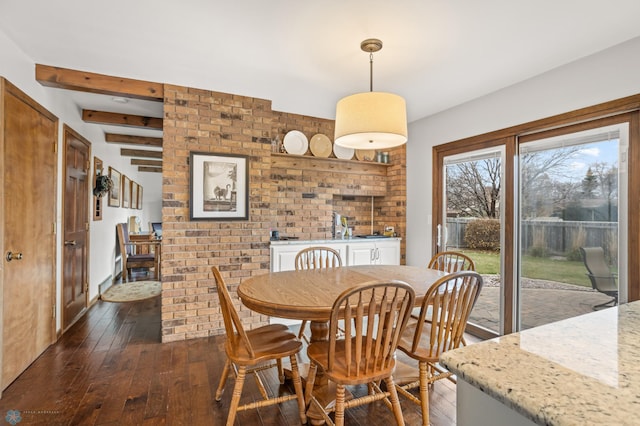 dining area with beamed ceiling, brick wall, and dark hardwood / wood-style flooring