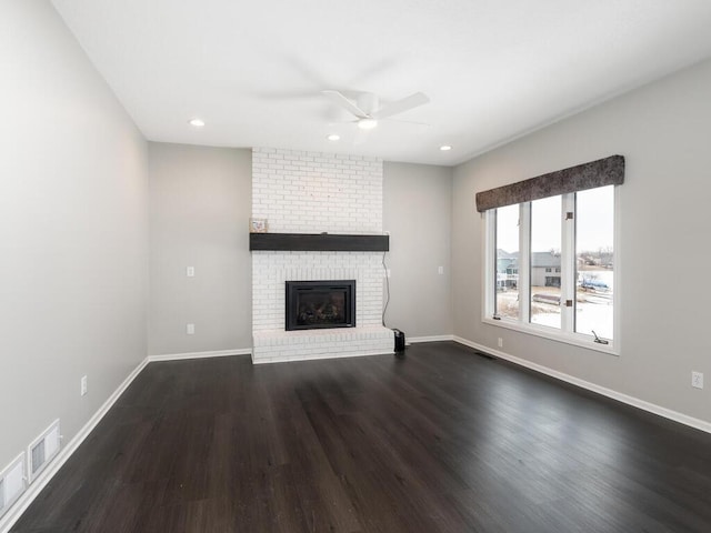 unfurnished living room featuring dark wood-type flooring, a fireplace, and ceiling fan