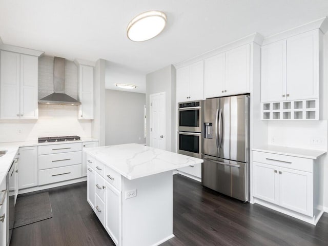 kitchen featuring a kitchen island, white cabinets, light stone counters, stainless steel appliances, and wall chimney range hood