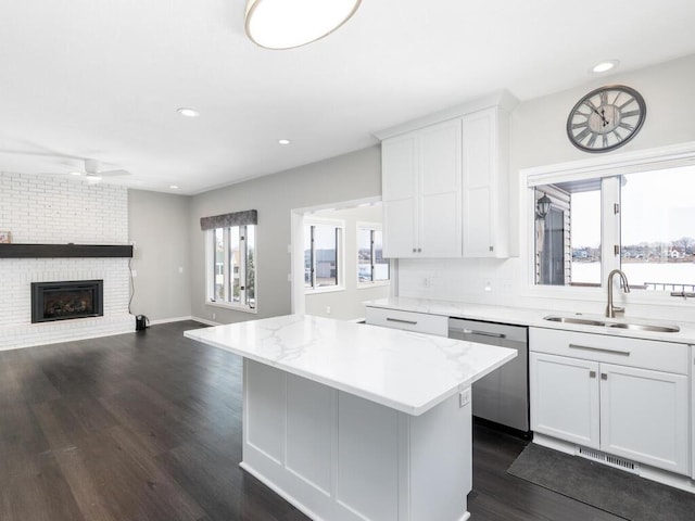 kitchen with dishwasher, sink, white cabinets, a center island, and dark wood-type flooring