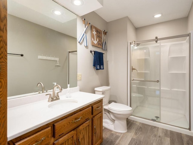 bathroom featuring a shower with door, vanity, hardwood / wood-style floors, and toilet