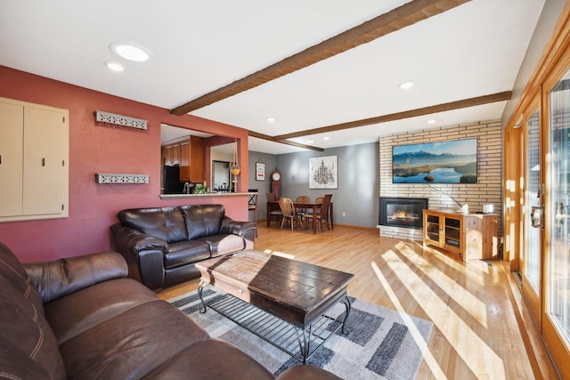 living room with beam ceiling, a fireplace, and light hardwood / wood-style floors