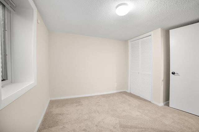 unfurnished bedroom with light colored carpet, a textured ceiling, and a closet