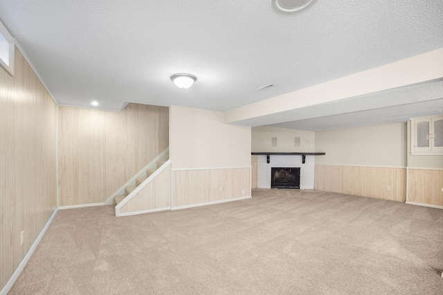 basement with light carpet, a textured ceiling, and wood walls