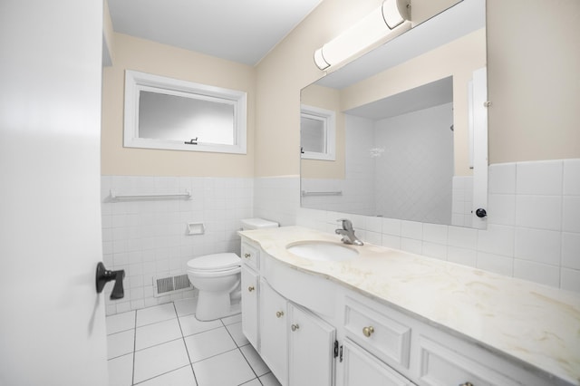 bathroom with vanity, toilet, tile patterned flooring, and tile walls