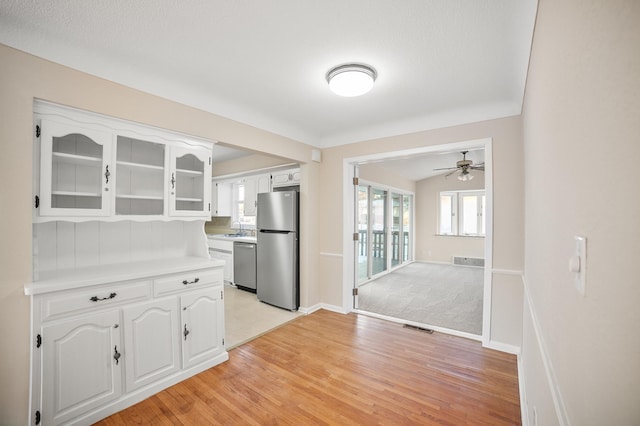 kitchen featuring sink, light hardwood / wood-style flooring, white cabinetry, stainless steel appliances, and vaulted ceiling