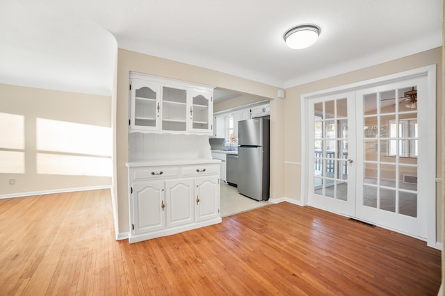 kitchen featuring appliances with stainless steel finishes, white cabinetry, sink, light hardwood / wood-style flooring, and french doors