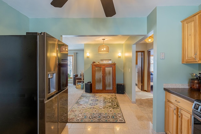 kitchen with light brown cabinets, a ceiling fan, appliances with stainless steel finishes, dark countertops, and decorative light fixtures