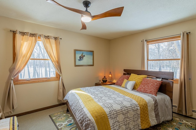 carpeted bedroom featuring a baseboard radiator, baseboards, ceiling fan, and a textured ceiling