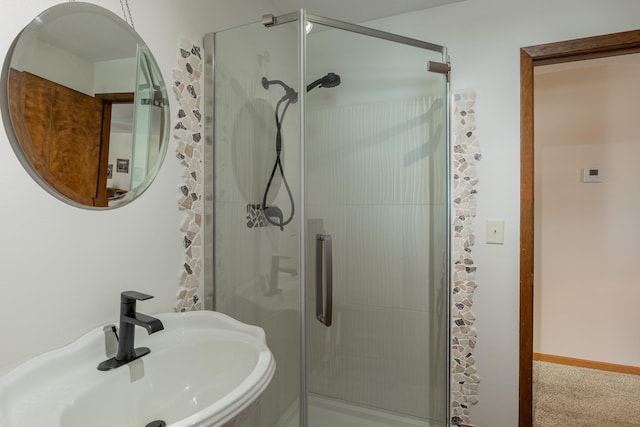 bathroom featuring a shower stall, baseboards, and a sink