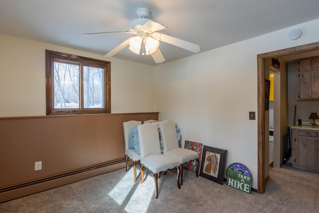 sitting room featuring a baseboard heating unit, a textured ceiling, a ceiling fan, and light colored carpet