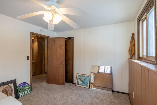 bedroom featuring a closet, multiple windows, a ceiling fan, and light colored carpet