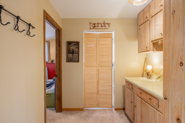 kitchen with light colored carpet, baseboards, light countertops, and light brown cabinets