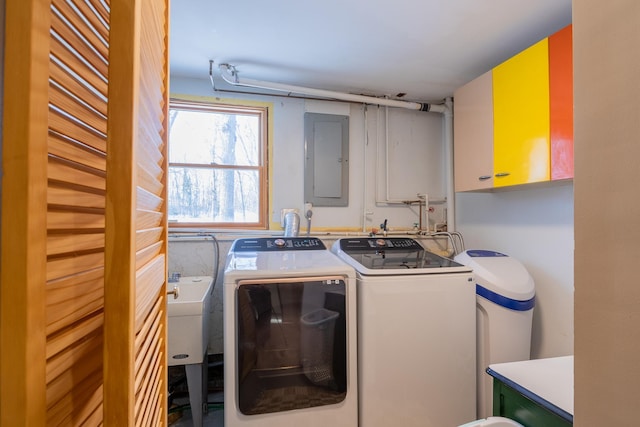 washroom with electric panel, cabinet space, independent washer and dryer, and a sink