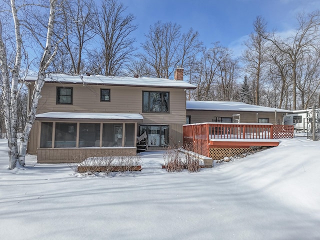 exterior space with a chimney, a sunroom, and a deck