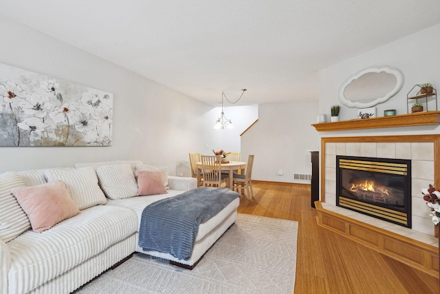 living room with a fireplace, light hardwood / wood-style flooring, and a notable chandelier