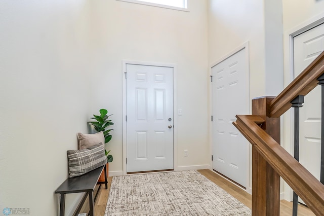 entryway featuring a towering ceiling and light hardwood / wood-style flooring