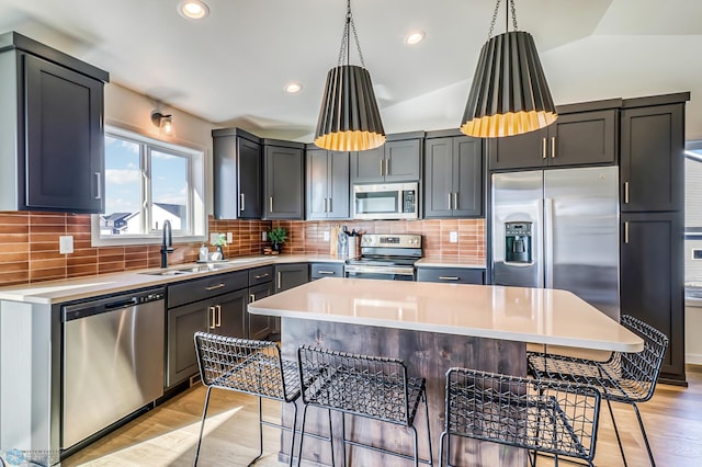 kitchen featuring hanging light fixtures, vaulted ceiling, appliances with stainless steel finishes, and a kitchen breakfast bar