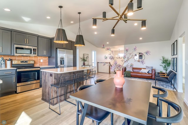 kitchen with a kitchen island, appliances with stainless steel finishes, decorative light fixtures, backsplash, and a notable chandelier