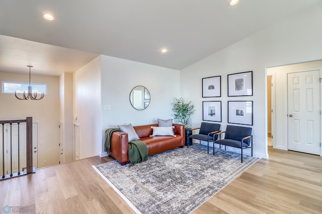 living room featuring an inviting chandelier, vaulted ceiling, and light hardwood / wood-style flooring