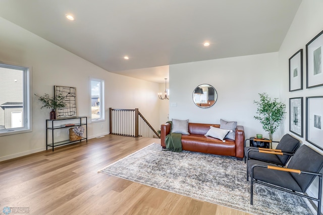 living room featuring lofted ceiling, light hardwood / wood-style floors, and a chandelier