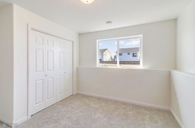 unfurnished bedroom with light colored carpet and a closet