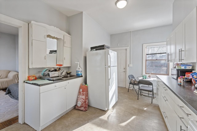 kitchen with white cabinetry, white fridge, sink, and built in desk