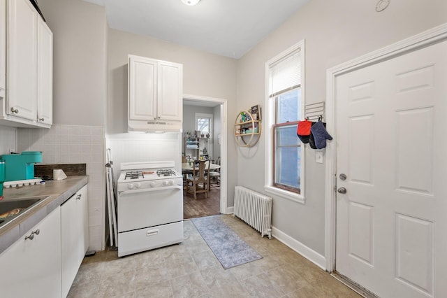 kitchen featuring white cabinetry, radiator, white gas range oven, and tasteful backsplash